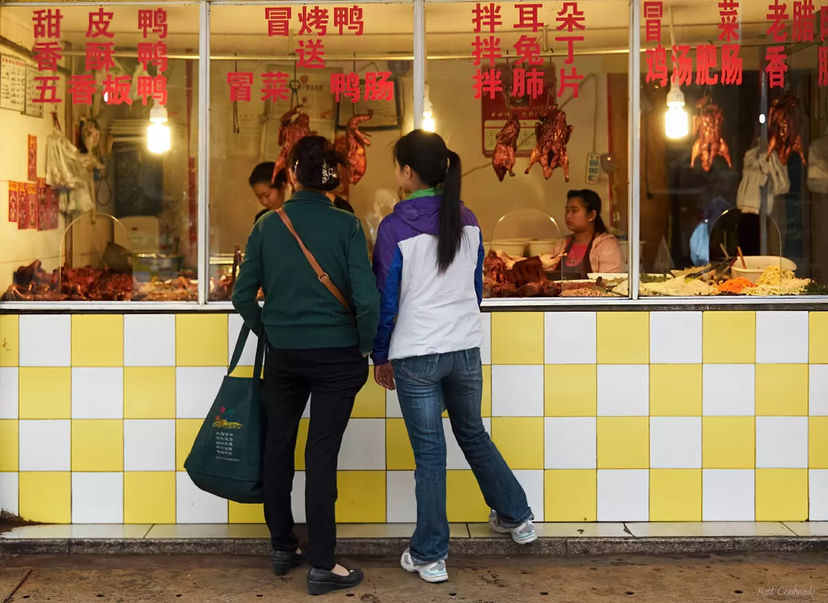 two women ordering roast duck at a chinese open air market