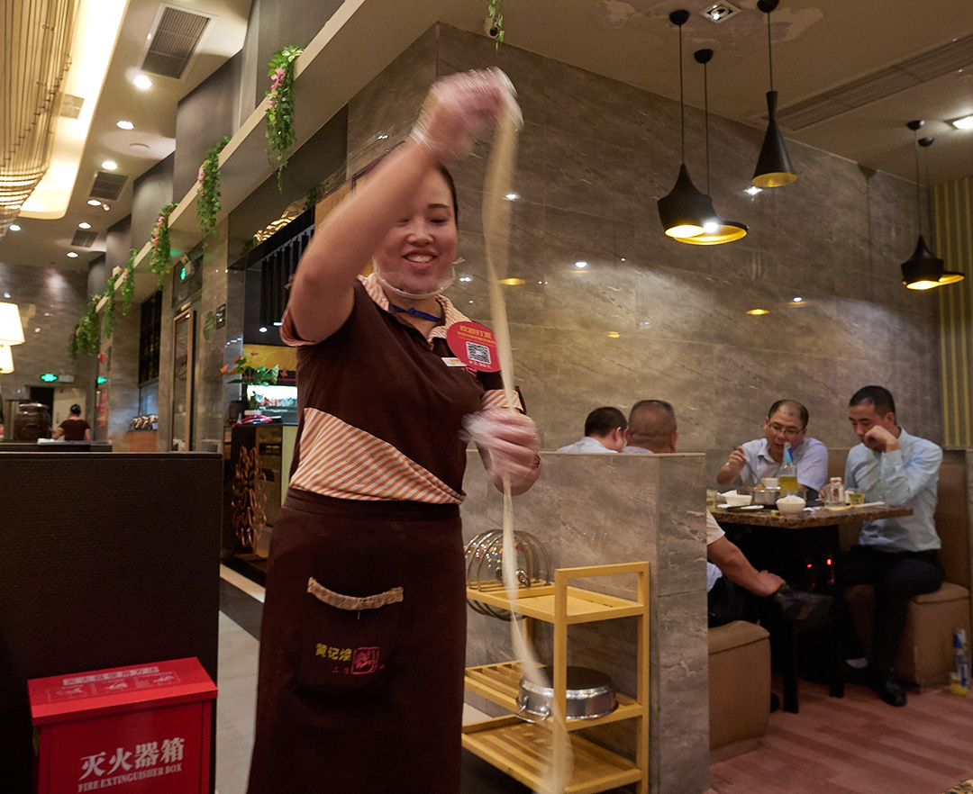 A server making fresh noodles at my table