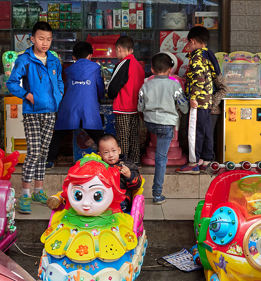 Kids playing arcade games outside of a shop