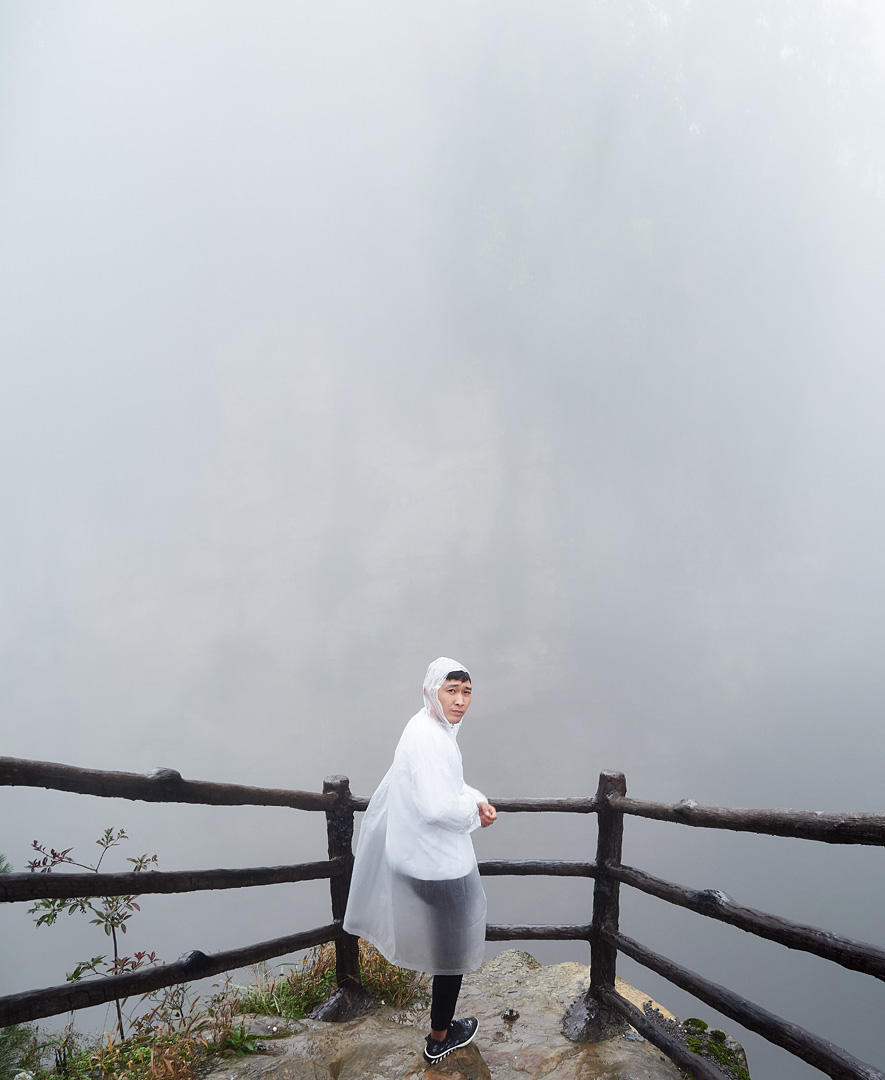 a main ina white raincoat in front of a wall of fog