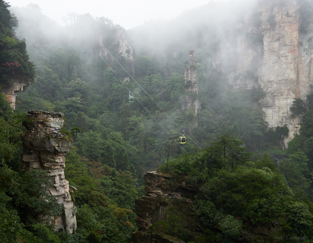 A gondola climbing through a foggy Zhangjiajie valley